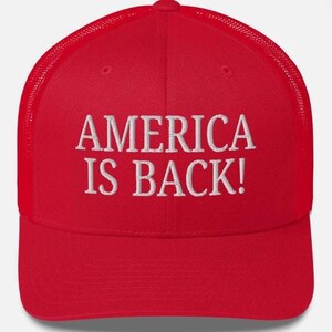 Puede incluir: Gorra de camionero roja con texto bordado en blanco "AMERICA IS BACK!". La gorra tiene una parte trasera de malla y una visera curva.