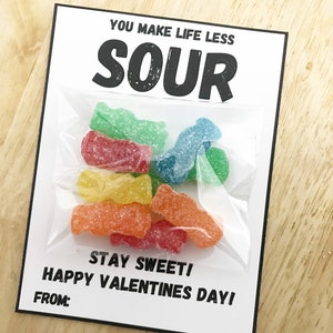 Könnte beinhalten: Eine weiße Karte mit schwarzem Text, der "You make life less sour. Stay sweet! Happy Valentines Day! From:" lautet. An der Karte ist eine durchsichtige Plastiktüte mit verschiedenen sauren Süßigkeiten befestigt.