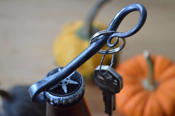 A blacksmith-forged keychain opener with 70 favorites and a proven groomsmen-gift track record — rugged, personal, and actually useful.