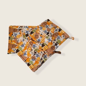Könnte beinhalten: Set mit vier Topflappen im Star Wars-Design. Die Topflappen sind aus Stoff und zeigen ein Muster mit den Figuren Chewbacca, Yoda und R2-D2. Die Topflappen sind mit Schnur zusammengebunden.