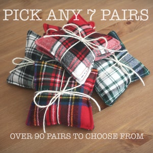 May include: A close-up of seven pairs of plaid fabric star-shaped pouches tied with twine. The text "PICK ANY 7 PAIRS" is at the top of the image and the text "OVER 90 PAIRS TO CHOOSE FROM" is at the bottom of the image.
