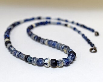 May include: A necklace made of blue and white glass beads. The beads are small and round, and they are strung together on a thin cord. The necklace is about 18 inches long.