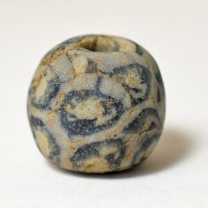 以下が含まれることがあります： 渦巻き模様の入った、丸い青と白のガラスビーズ。ビーズの中央には、糸を通すための穴が開いています。