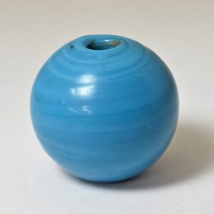 Könnte beinhalten: Eine hellblaue Glasperle mit einem Wirbelmuster.