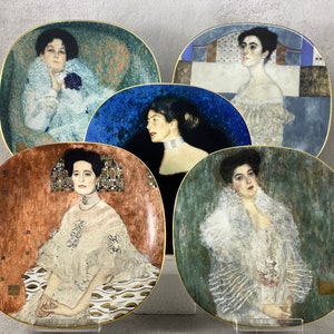 May include: Five decorative ceramic plates with gold trim, each featuring a portrait of a woman in a white dress against a colorful background.