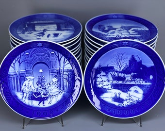 May include: A set of 10 blue and white Royal Copenhagen Christmas plates. The plates feature winter scenes with a castle, a sleigh, and a Christmas tree. The plates are numbered 1990 and 1996.