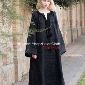 May include: A black embroidered linen dress with long sleeves and a round neckline. The dress has a geometric pattern and a tassel detail at the neckline. The model is wearing white sneakers. etsy.com/shop/HelenCloth Real Photo