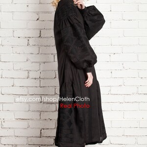 Pu&ograve; includere: Abito in lino nero ricamato con maniche lunghe e gonna a pieghe. L'abito &egrave; mostrato su una modella contro un muro di mattoni bianchi. Il testo "etsy.com/shop/HelenCloth Real Photo" &egrave; visibile nella parte inferiore dell'immagine.