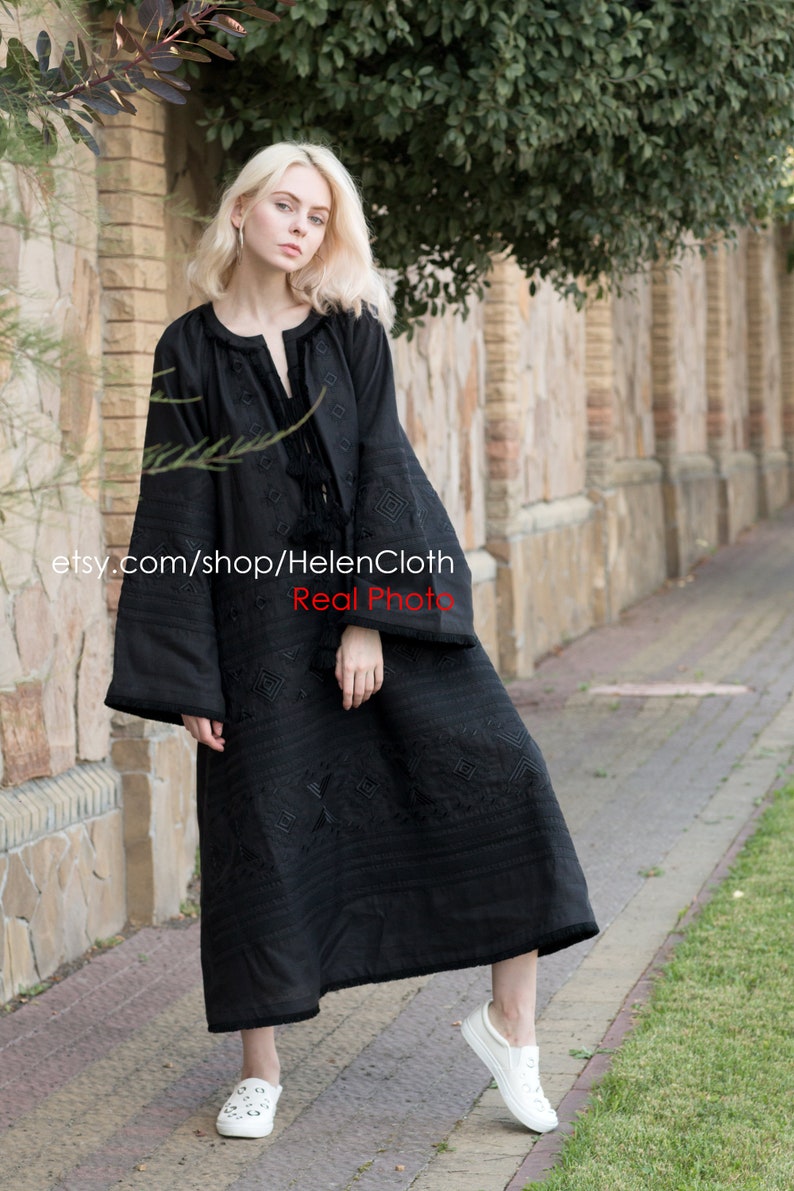May include: A black embroidered dress with long sleeves and a loose fit. The dress has a geometric pattern and a tassel detail at the neckline. The model is wearing white sneakers. etsy.com/shop/HelenCloth Real Photo