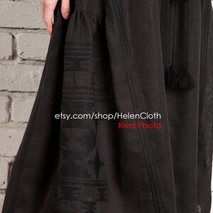 Pu&ograve; includere: Abito nero in lino con dettagli ricamati e nappine. L'abito ha una gonna fluida e un corpetto aderente. L'abito &egrave; mostrato su una modella contro un muro di mattoni bianchi. etsy.com/shop/HelenCloth Real Photo
