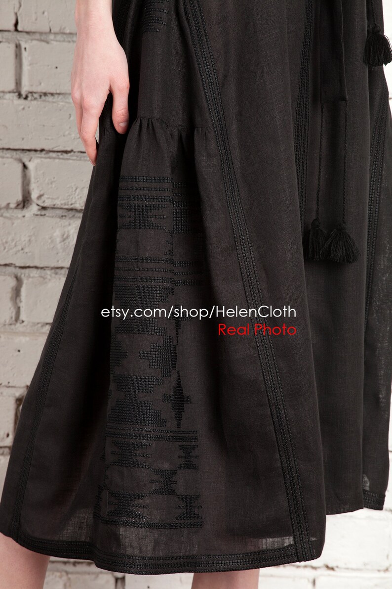 Pu&ograve; includere: Abito nero in lino con dettagli ricamati e nappine. L'abito ha una gonna fluida e un corpetto aderente. L'abito &egrave; mostrato su una modella contro un muro di mattoni bianchi. etsy.com/shop/HelenCloth Real Photo