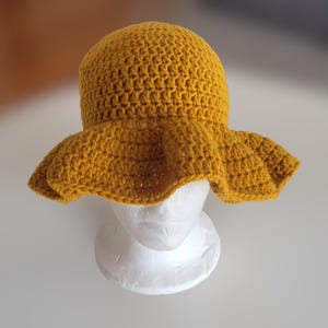 May include: A yellow crocheted sun hat with a wide brim.