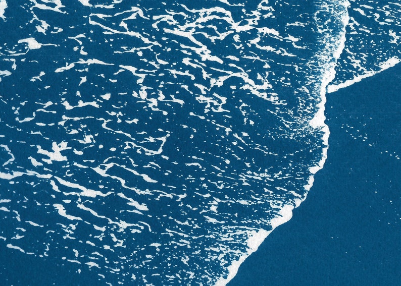 Puede incluir: Primer plano de una ola rompiendo en la costa, creando una cresta blanca espumosa sobre un fondo de oc&eacute;ano azul profundo.
