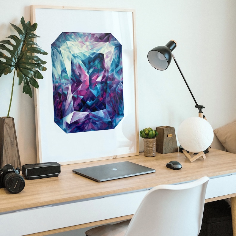 Puede incluir: Una impresi&oacute;n enmarcada de una gran gema geom&eacute;trica abstracta, de color p&uacute;rpura, azul y verde. La impresi&oacute;n est&aacute; colgada en una pared blanca sobre un escritorio con una computadora port&aacute;til, una l&aacute;mpara y una planta en maceta.