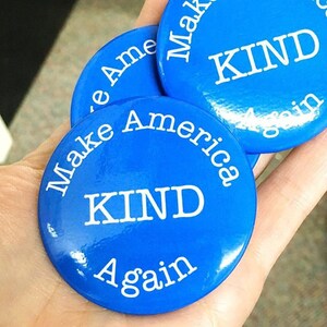 May include: Three blue round buttons with white text that reads "Make America Kind Again".