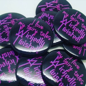 May include: A collection of black and purple round buttons with the text "I love my fairy tales wickedly twisted" printed on them.
