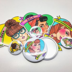May include: A set of four colorful pinback buttons featuring illustrations of women with different hairstyles and text. The buttons are surrounded by stickers with similar designs and text, including "My Curves Are", "Sola", and "Geek Chic".