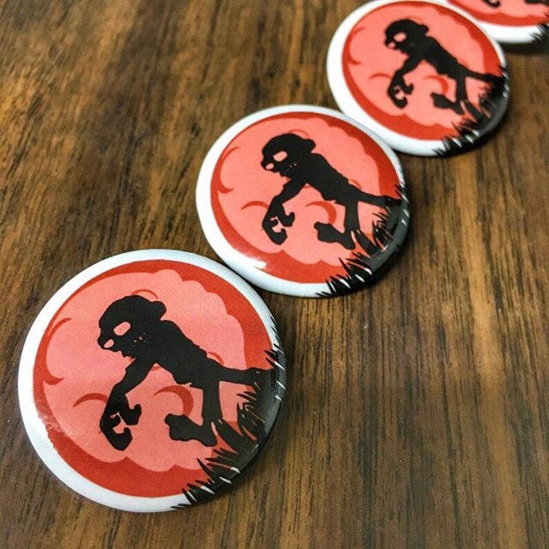 May include: Four round red and white buttons with a black silhouette of a creature walking on a red background. The creature is walking to the right and has a large head and small body.