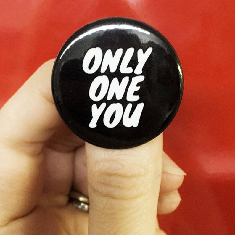 May include: Black and white button with the text "ONLY ONE YOU" in white lettering.