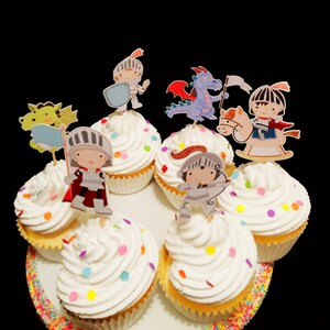 May include: A set of six cupcakes decorated with colorful sprinkles and topped with various character toppers, including a knight, a dragon, and a unicorn. The cupcakes are arranged on a white plate with a colorful sprinkle border.