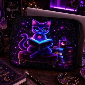May include: A black laptop sleeve featuring a purple cat wearing glasses and reading a book, set against a starry night sky. A coffee cup, books, and the words "Stay Magical" are also visible. The overall theme is magical and mystical.