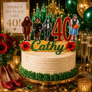 May include: A decorated cake with a Wizard of Oz theme, featuring character cutouts and a "40" topper. The cake is on a gold stand, with red shoes and champagne glasses in the foreground. The cake has a "Cathy" topper.