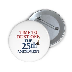 May include: White button with the text "TIME TO DUST OFF THE 25th AMENDMENT" in red and blue. A small broom graphic is next to the word "25th". A second button is visible in the background.