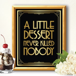 May include: A framed art print with the text "A Little Dessert Never Killed Nobody" in gold lettering on a black background. A sundae with a cherry sits to the left, and white flowers are on the right.
