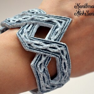 Puede incluir: Un brazalete de color plateado con un dise&ntilde;o geom&eacute;trico. El brazalete est&aacute; hecho de un material tejido y tiene una superficie texturizada. El brazalete est&aacute; hecho a mano por AlekSanta.