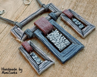 May include: A set of handmade polymer clay earrings and a necklace. The earrings and necklace feature a rectangular design with a wood grain pattern. The earrings have a black and grey rectangle inside the frame, while the necklace has a black and grey rectangle inside the frame and a red rectangle on top. The necklace has a brown leather cord.