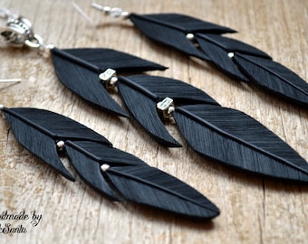 May include: A set of black feather earrings and a necklace with a silver pendant. The feathers are layered and have silver beads.