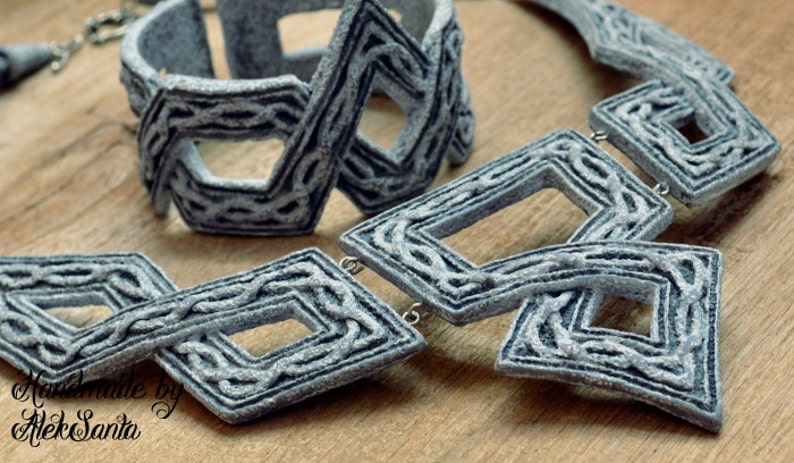 Puede incluir: Un conjunto de collar y pulsera gris geom&eacute;trico con un dise&ntilde;o tejido. Las joyas est&aacute;n hechas de arcilla polim&eacute;rica y tienen un acabado texturizado.