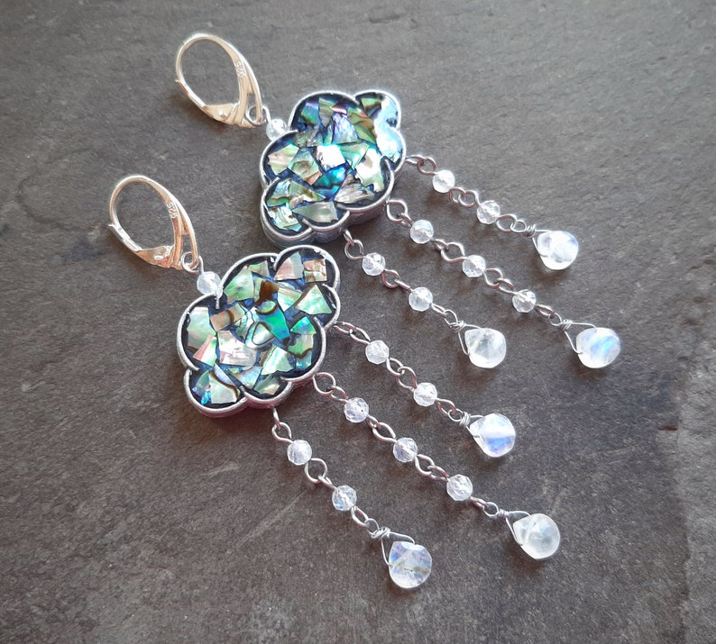 May include: A pair of silver dangle earrings with a cloud-shaped abalone shell design and iridescent moonstone drops.