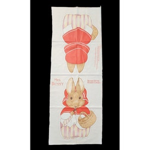 May include: A fabric pattern for sewing a Mrs. Bunny doll. The pattern includes a red dress with white stripes, a white apron, and a basket. The pattern is from the Beatrix Potter Nursery Classics collection.