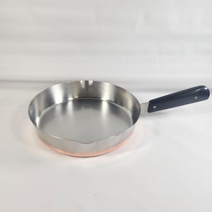 May include: A small copper-bottomed stainless steel frying pan with a black plastic handle.