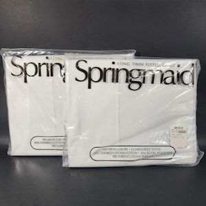 May include: Two packages of white Springmaid long twin fitted sheets. The packaging includes the brand name in a dark font. The sheets are labeled as no-iron luxury, made of combed cotton and Kodel polyester, with a 180 thread count.
