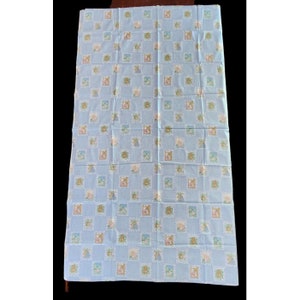 May include: A blue fabric with a repeating pattern of small squares. Each square contains a cartoon image of a bear, a rabbit, or a bird. The fabric is likely intended for use in a baby's nursery or bedroom.