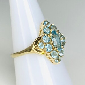 May include: A gold ring with a large marquise-shaped blue topaz surrounded by smaller round blue topaz stones.