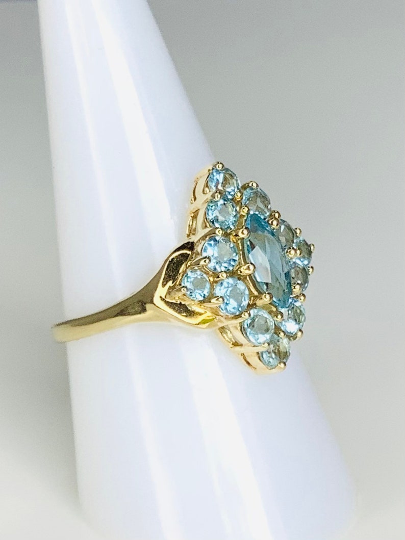 May include: A gold ring with a large marquise-shaped blue topaz surrounded by smaller round blue topaz stones.