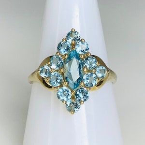May include: A gold ring with a large marquise-shaped blue topaz gemstone surrounded by smaller round blue topaz gemstones.