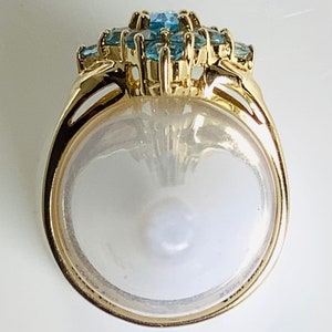 May include: A gold ring with a cluster of blue topaz stones set in a floral design.