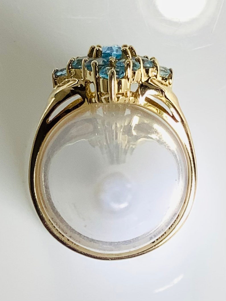 May include: A gold ring with a cluster of blue topaz stones set in a floral design.