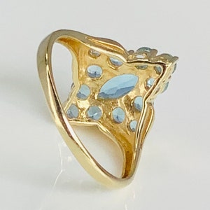 May include: A gold ring with a large blue gemstone surrounded by smaller blue gemstones.