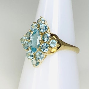 May include: A gold ring with a cluster of light blue gemstones in a diamond shape.