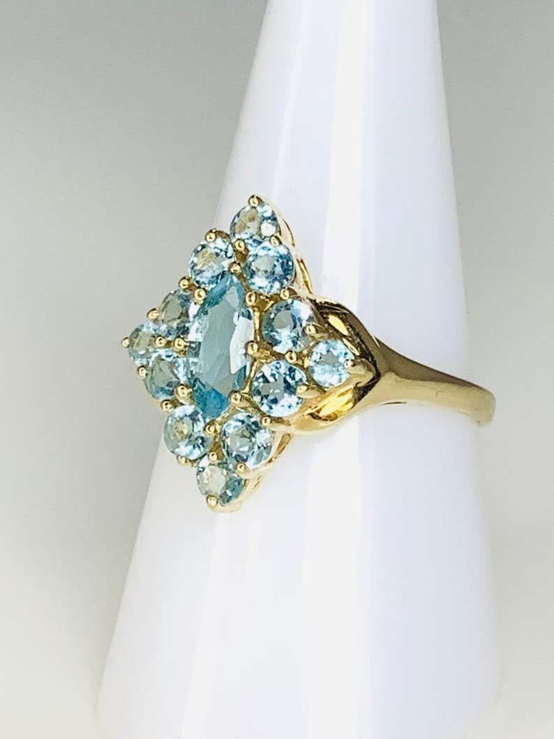 May include: A gold ring with a cluster of light blue gemstones in a diamond shape.
