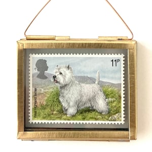 Peut inclure: Un timbre-poste vintage encadré représentant un West Highland White Terrier avec le texte "West Highland Terrier" et "11p" imprimé sur le timbre.
