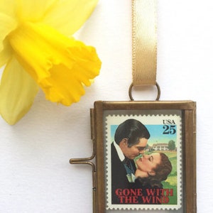 K&ouml;nnte beinhalten: Ein Messingrahmen-Medaillon mit einer Vintage-Briefmarke von Gone With The Wind mit Clark Gable und Vivien Leigh. Die Briefmarke ist eine 25-Cent-Briefmarke der USA.