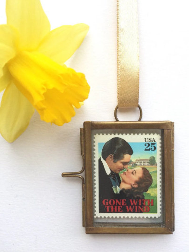 K&ouml;nnte beinhalten: Ein Messingrahmen-Medaillon mit einer Vintage-Briefmarke von Gone With The Wind mit Clark Gable und Vivien Leigh. Die Briefmarke ist eine 25-Cent-Briefmarke der USA.