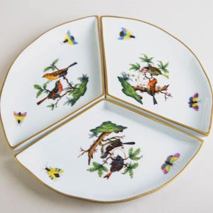 Puede incluir: Un juego de tres fuentes de porcelana blanca. Cada fuente presenta un diseño diferente de pájaros y mariposas coloridas con ribete dorado. Las fuentes están dispuestas en un patrón circular, ideal para aperitivos o postres.