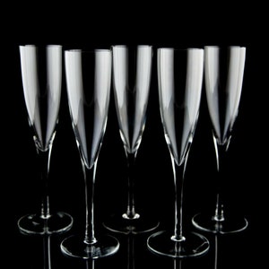 May include: Five clear champagne flutes with long stems and wide bowls are arranged in a row against a black background. The glasses are empty and reflect the light, creating a sense of elegance and sophistication.